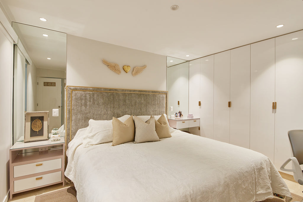 Foto de un dormitorio principal. Tiene una cama doble y un closet a lo largo de una de las paredes; ambos son de color blanco. Sobre la cabecera de la cama hay un adorno de madera en forma de un corazón con alas.