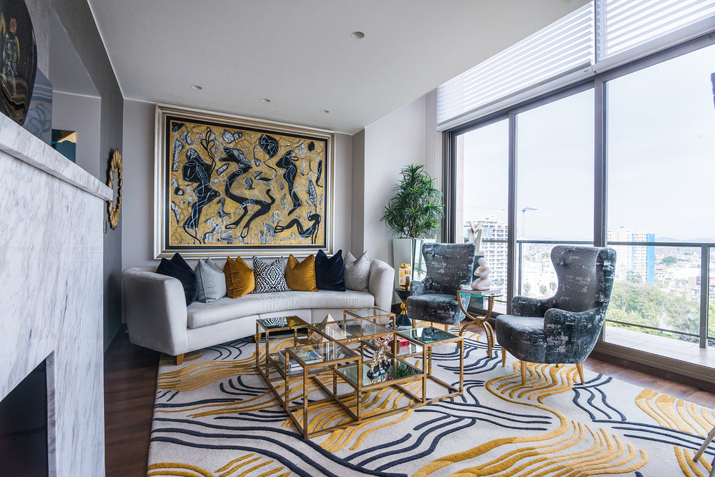 Foto de una sala principal. Hay un sillón largo y dos pequeños al rededor de una mesa decorativa. Una de las paredes está cubierta por un gran ventanal que da a un balcón.