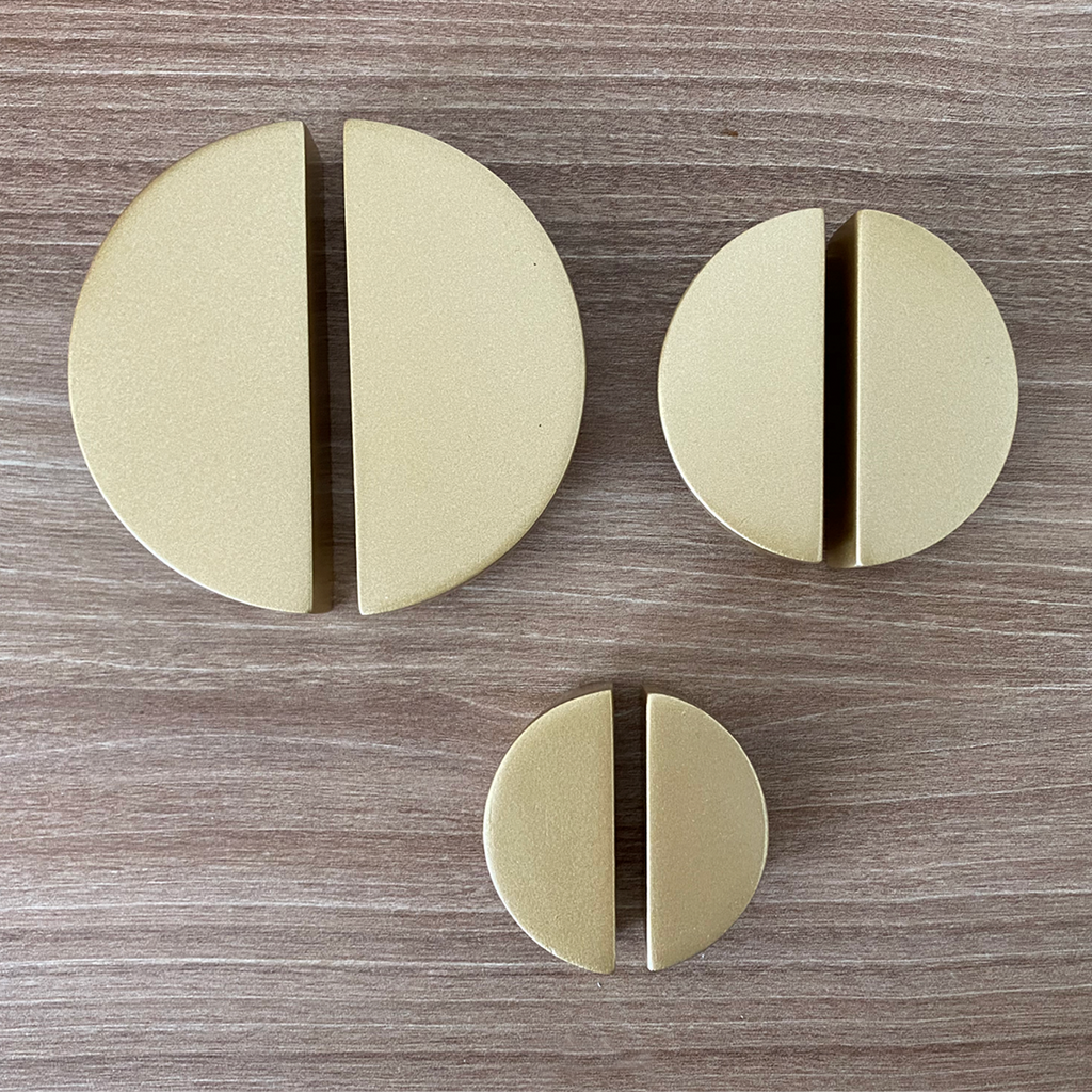 Foto de un mismo tipo de jalador en tres tamaños distintos. Son redondos, separados en el centro, y de color dorado. 